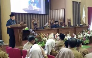 Tanah Bumbu – Pemerintah Kabupaten (Pemkab) Tanah Bumbu bersama Dewan Perwakilan Rakyat Daerah (DPRD) setempat tengah menyusun regulasi guna memperkuat riset dan inovasi daerah. Langkah ini dibahas dalam Rapat Paripurna DPRD Tanah Bumbu, Selasa (4/3/2025), yang membahas Rancangan Peraturan Daerah (Raperda) tentang Riset dan Inovasi Daerah. Bupati Tanah Bumbu, Andi Rudi Latif, melalui Asisten Perekonomian dan Pembangunan Pemkab Tanah Bumbu, Eryanto Rais, menegaskan bahwa riset dan inovasi memiliki peran strategis dalam mendorong kemajuan daerah. “Riset dan inovasi berperan penting dalam meningkatkan daya saing, kualitas pelayanan publik, serta menghadirkan solusi atas tantangan pembangunan,” ujarnya. Regulasi ini nantinya akan menjadi dasar hukum bagi pengembangan riset di berbagai sektor, seperti pendidikan, kesehatan, pertanian, industri, dan lingkungan hidup. Selain itu, Raperda ini juga selaras dengan visi pembangunan Kabupaten Tanah Bumbu, yakni BerAksi (Akomodatif, Kerja, Sistematis, dan Inovatif) untuk mewujudkan daerah yang maju, makmur, dan beradab. Pemkab Tanah Bumbu menargetkan penyelenggaraan riset dan inovasi yang melibatkan berbagai pihak, termasuk pemerintah, akademisi, dunia usaha, dan masyarakat. Hal ini sejalan dengan Peraturan Presiden Nomor 33 Tahun 2021 tentang Badan Riset dan Inovasi Nasional. Bupati yang akrab disapa Bang Arul ini menekankan pentingnya infrastruktur riset yang kuat, baik dari segi fasilitas, sumber daya manusia, maupun sistem pendanaan yang transparan dan akuntabel. “Kami ingin regulasi ini benar-benar memberikan kepastian hukum serta mendorong ekonomi berbasis pengetahuan,” tambahnya. Ia juga mengajak DPRD Tanah Bumbu untuk bersama-sama mengkaji Raperda ini agar menghasilkan regulasi yang berkualitas dan dapat diimplementasikan secara efektif. Rapat Paripurna ini dipimpin oleh Wakil Ketua DPRD Tanah Bumbu, Syabani Rasul, serta dihadiri unsur Forum Koordinasi Pimpinan Daerah (Forkopimda) dan Kepala SKPD Pemkab Tanah Bumbu.